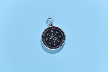 Compass on blue bright background. Travel, adventure flat lay. Top view