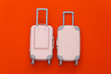 Two toy travel luggage on orange background. Travel planning. Top view. Flat lay