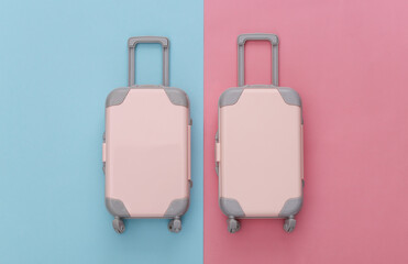Two toy travel luggage on pink blue pastel background. Travel planning. Top view. Flat lay