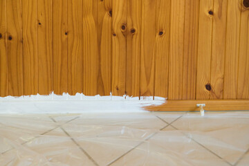 Painting timber tongue and groove wall with plastic drop sheet on floor to protect tiles