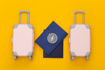 Travel planning. Two toy travel luggage and passport, compass on yellow background. Top view. Flat lay
