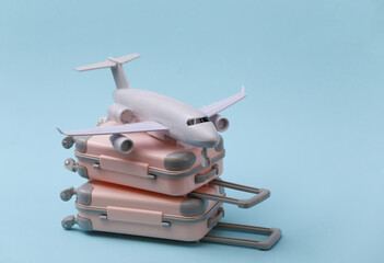 Travel, vacation or tourism concept. Two mini travel luggage suitcase and air plane on a blue background