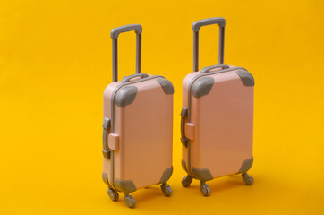 Travel still life, vacation or tourism concept. Two mini travel luggage suitcase on yellow background