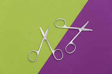 Two pairs of nail scissors on green purple background. Top view