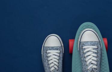Cruiser board with sneakers on a classic blue background. Youth entertainment. Top view. Flat lay