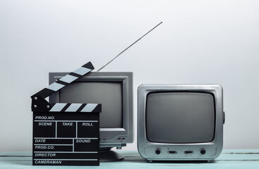 Old tv receivers with movie clapperboard on white wall background. Entertainment Industry, Media
