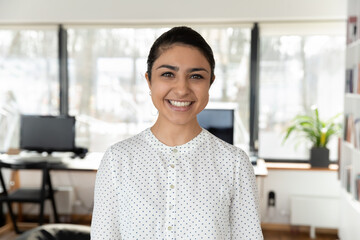 Headshot portrait of smiling indian female employee look at camera pose in office, profile picture of happy millennial biracial woman worker show confidence success at workplace, leadership concept - Powered by Adobe