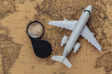 Magnifying glass and air plane on old map. Travel, adventure concept