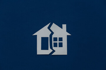 The concept of separation of property, divorce. Paper house cut in half on a classic blue background
