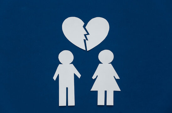 The concept of divorce. Paper figures of man and woman and broken heart on a classic blue background.