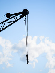 crane with hook, blue sky and white clouds in background
