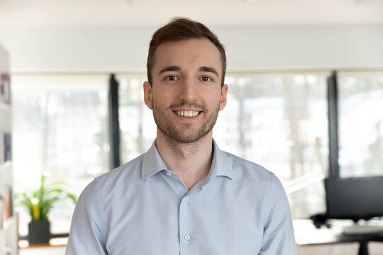 Profile picture of happy young Caucasian male employee worker look at camera posing in office workplace, headshot portrait of smiling businessman boss show confidence and success, leadership concept