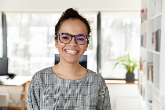 Headshot portrait of happy african American businesswoman in glasses look at camera pose in office, smiling biracial young female employee in spectacles show leadership and success qualities