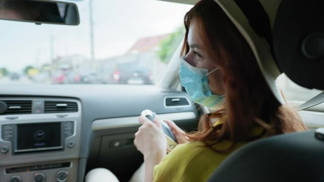 weekend coronavirus, young female photographer in straw hat and medical mask uses retro camera and photographs her family while traveling in car