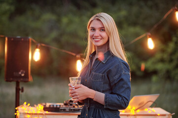 Happy young blond female with long hair having drink a nd looking at you