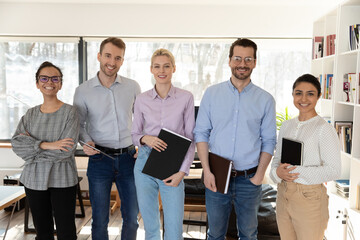 Portrait of smiling multiracial businesspeople posing together in office, show unity and support in...