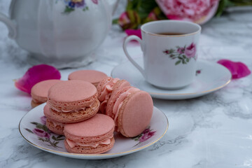 Pink strawberry macarons with tea. French delicate dessert.