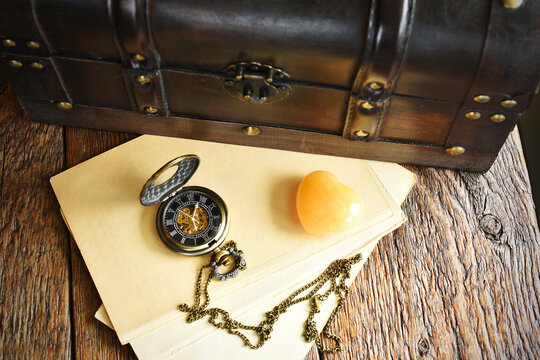 A close up image of an old wooden travel trunk and vintage pocket watch and letters.