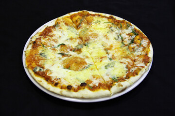 Pizza with four pieces of cheese and basil leaves on a white plate