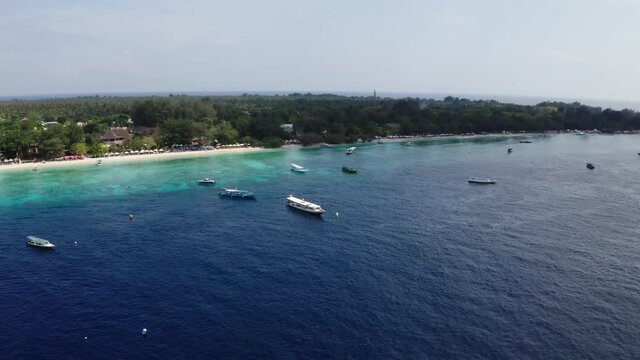 Summer time in the Gili Travangan Island with cruise boats. The drone shot of the island nearby.