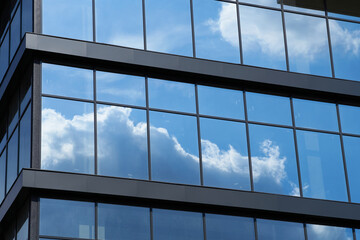 facade of a modern building on a bright Sunny day, blue sky and clouds reflecting in a glass, beautiful exterior of the new building