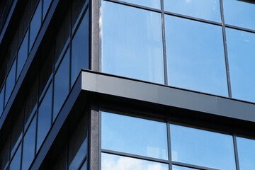 facade of a modern building on a bright Sunny day, blue sky and clouds reflecting in a glass, beautiful exterior of the new building