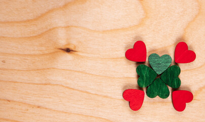 A four-leaf clover of four green and red hearts is laid out on a wooden background