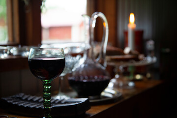A wine glass with a carafe filled with wine and a candle 