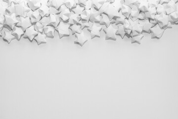 Light background of white matte paper stars located on top and an empty place for text.