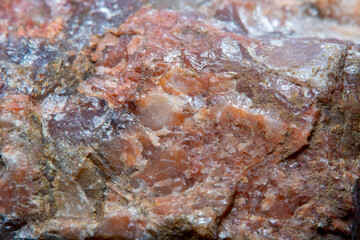 Obraz na płótnie Canvas Photograph of a granite surface interspersed with transparent mica in soft focus at high magnification. Fine texture of natural mineral of pink color with blurred background.
