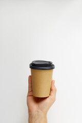 Male hand holding a take away coffee paper cup isolated on white background