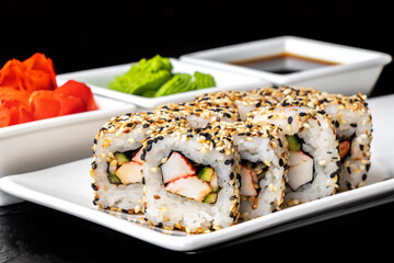 Rolls with crab meat, cucumber and sesame seeds on a white plate on a dark background. Sushi menu. Japanese food.