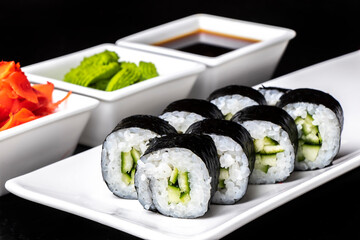 Vegetarian Rolls with cucumber on a white plate on a dark background. Sushi menu. Japanese food.