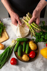 Men taking out fresh organic asparagus from cotton shopping bag