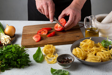 Hands chopping tomato for pasta cooking