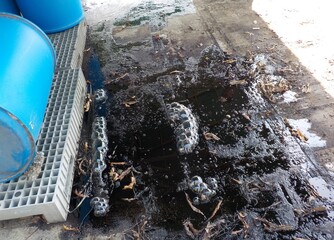 Black liquid chemicals leaking from the tank into the floor.