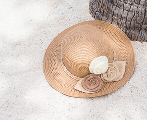 Fototapeta na wymiar Close up hat on sand beach and under coconut tree. Accessories travel summer holidays concept.