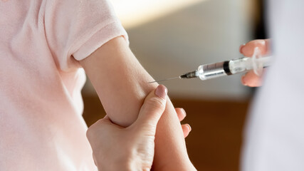 Close up female hands holding syringe, doctor vaccinating little patient at meeting in clinic, therapist pediatrician gp making prick, injection to preschool girl, children healthcare concept