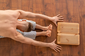 Shirtless young sportsman bending forwards with his arms and legs stretched