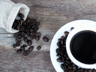 Coffee beans in a white glass And the coffee beans fell around on the wooden floor.