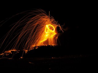 Abstract,Long exposure of swirling flame sparks arcing in circle at the night is black background.