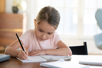 Busy little girl writing or drawing with pen in notebook close up, pretty focused child schoolgirl...