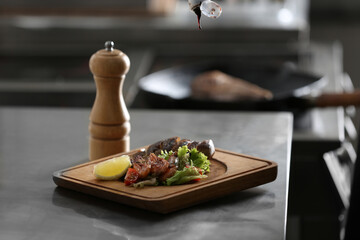 Adding sauce to tasty meal on table in restaurant kitchen. Cooking food