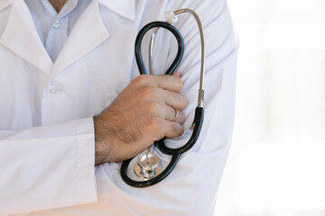 Close up male doctor wearing white coat uniform holding stethoscope in hand, cardiologist or...