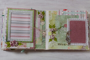 Scrapbooking wedding photoalbum spread with green paper decorative elements, flowers, beads, tapes, ribbons, hearts and frames for phographs.
