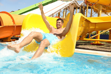 Man on slide at water park. Summer vacation
