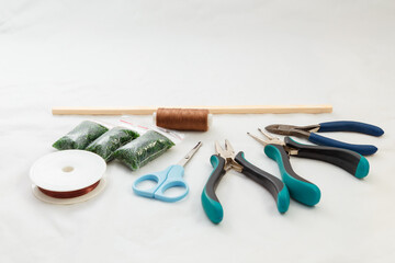 Set for handcraft, making of bijouterie, green beeds, scissors, spool of threads, pliers. Handmade jewelry concept.