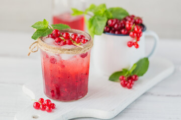 Glass jar of red currant soda drink on white wooden table. Summer healthy detox lemonade, cocktail or another drink background. Low alcohol, nonalcoholic drinks, vegetarian or healthy diet concept.