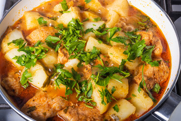 Cooking potatoes with chicken in a hot sauce, Italian cuisine - Arrabbiata garlic chicken with potatoes is cooked in a pan, close-up