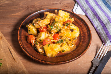 Italian cuisine - Arrabbiata garlic chicken with potatoes in a clay plate on the table, close-up, rustic style